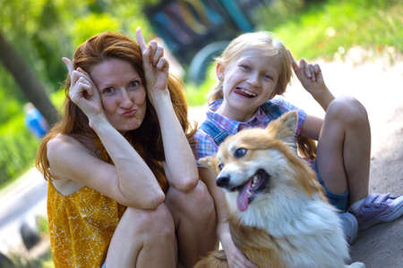 family. Mom, daughter and dog having fun in front of the camera outdoorsの写真素材