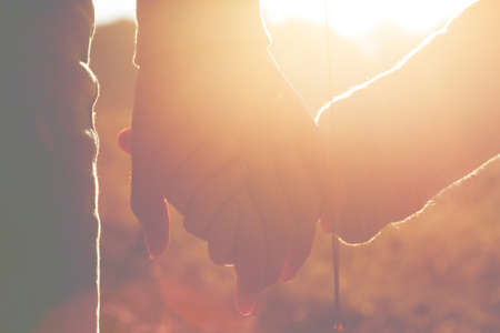 Mom and daughter are holding hands  at sunset lightの写真素材