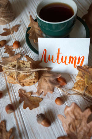 Beautiful autumn background - cup of tea, biscotti, autumn leaves and inscription Autumnの写真素材