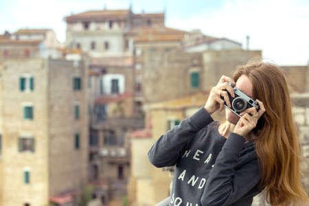 Girl with retro camera talking pictures outdoors, Italy, Pitigliano. Tuscanyの写真素材
