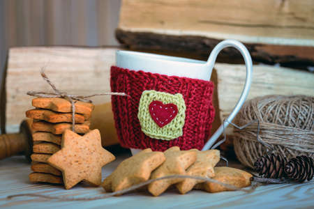 Knitted woolen cups on a wooden table and beautiful delicious christmas gingerbreadの写真素材