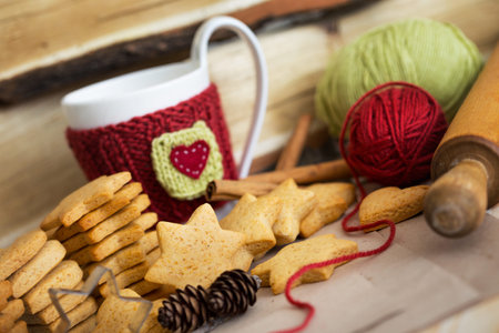 Knitted woolen cups on a wooden table and beautiful delicious christmas gingerbread