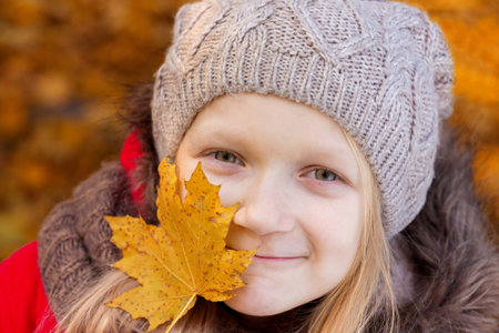 autumn - little girl holds a yellow maple leaf
