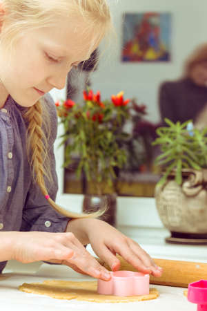 little girl makes a cookie in the kitchenの写真素材