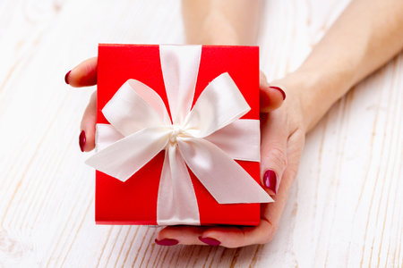 girl holding beautiful  gift for the day valentines day. red box and white bow 