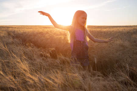 happy young girl joys at the wheat field at the evening timeの写真素材