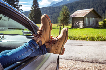 Girl legs in bright boots sticking out of the car. Dolomites, Italy.