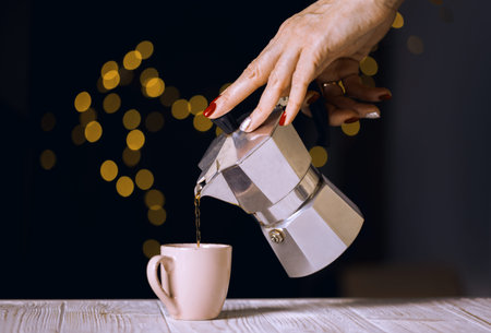 the girl pours coffee from a geyser coffee maker into a cup and bokeh in the backgroundの写真素材