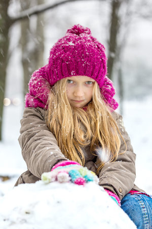 winter - little smiling girl outdoors at the snowfall time