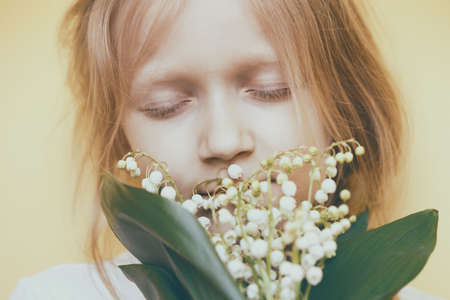 little girl with lilies of the valley in handsの写真素材