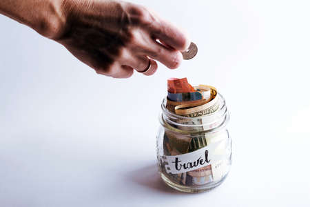 wanderlust. adventure concept.a girl puts a coin in  jar with moneyの写真素材