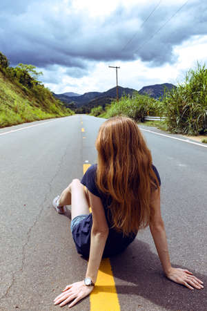 girl at the empty brazilian road at sunny cloudy dayの写真素材