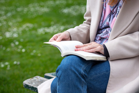 the girl is sitting on a park bench and reading a book