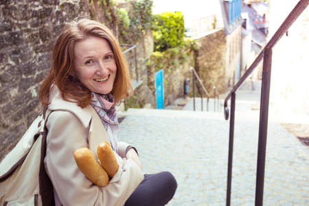 smiling French girl with baguettes on the street side of the city
の写真素材