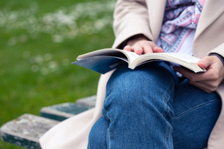 the girl is sitting on a park bench and reading a book
