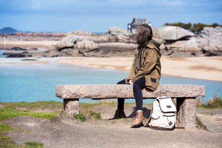 girl traveler sits on a bench near the sea and the shore at  the Tregastel, Brittany. France
の写真素材
