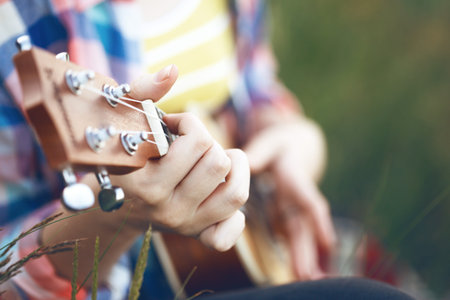girl playing on ukulele. hands playing a guitar close-up