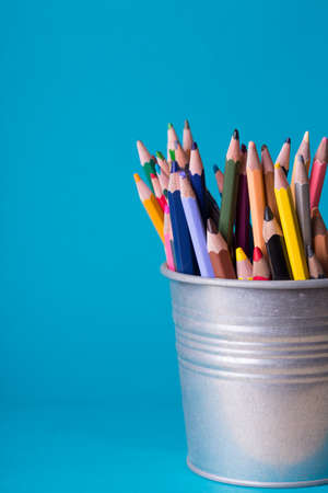 bucket with colorful pencils on a blue backgroundの写真素材