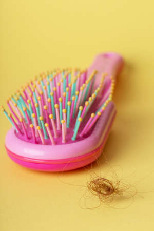 problem with hair. pink comb and drop-down hair on a yellow backgroundの写真素材