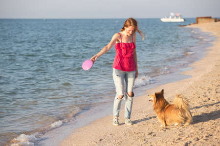happy fun weekend by the sea - girl playing with a dog on the beach. Summerの写真素材