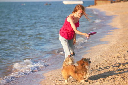 happy fun weekend by the sea - girl playing with a dog on the beach.の写真素材