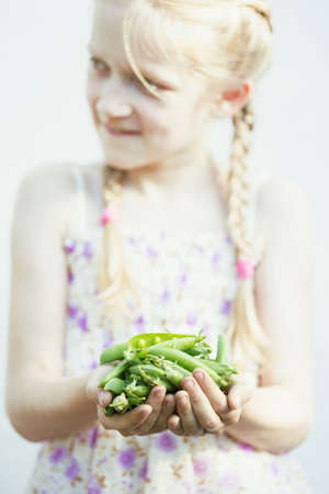 summer - the smiling girl is holding a green peas  in her handsの写真素材