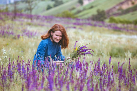 summer - beautiful girl on a meadow with a bouquet of wildflowers and traditional Ukrainian landscapeの写真素材