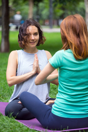 Happy girls doing yoga in the park on the grass. Healthy and Yoga Concept