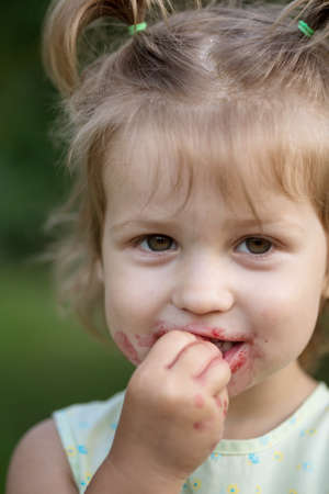 the little girl eats cherry in the garden. Summerの写真素材