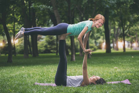 Close up hands. Happy girls doing yoga in the park on the grass. Healthy and Yoga Conceptの写真素材