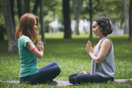 Close up hands. Happy girls doing yoga in the park on the grass. Healthy and Yoga Conceptの写真素材