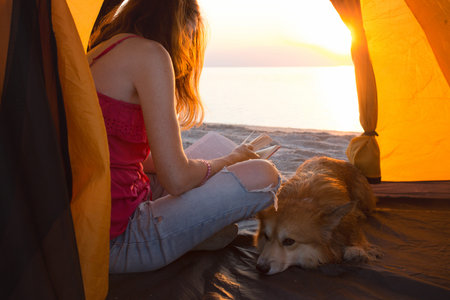 happy weekend by the sea - girl with a dog in a tent on the beach at dawn. Ukrainian landscape at the Sea of Azov, Ukraineの写真素材