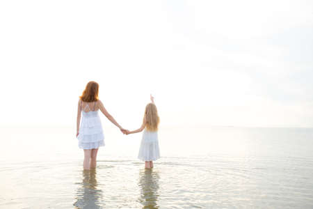 mother with daughter at the evening seaの写真素材