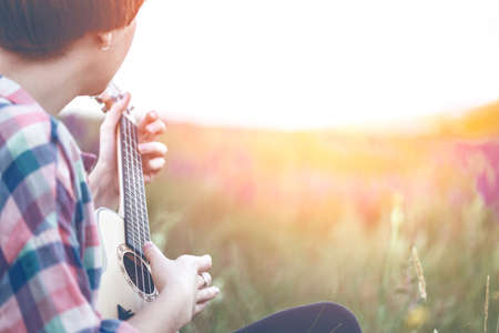 girl playing on ukulele. hands playing a guitar close-upの写真素材