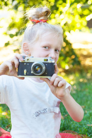 little pretty girl with retro camera outdoor