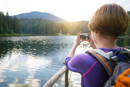 tourist girl making a photo shoot of  mountain lake synevyr. Carpathians,  Ukraine.の写真素材