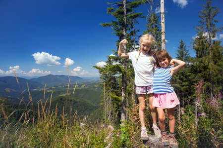 little children on a hike. Fun girlfriend on the background of a mountain landscapeの写真素材