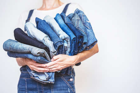 The girl holds a stack of jeans in her hands. cleaning in the closet.の写真素材