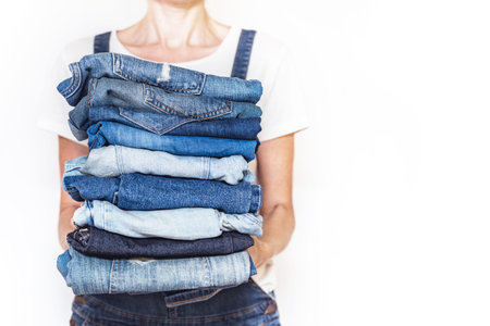 The girl holds a stack of jeans in her hands. cleaning in the closet.