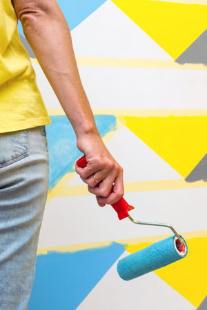 Interior Design. The girl paints the wall in geometric pattern.
