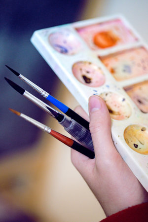 girl holds in her hand brush and watercolor paletteの写真素材