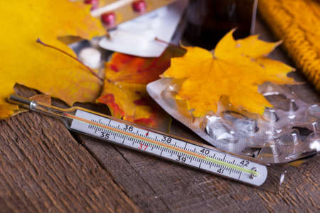 Fall and health care. cup of tea, pills and thermometer on a wooden backgroundの写真素材