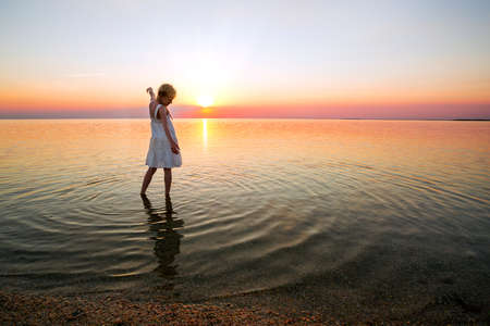 happy weekend by the sea - little girl looks at the sunset at the sea. Ukrainian landscape at the Sea of Azov, Ukraineの写真素材