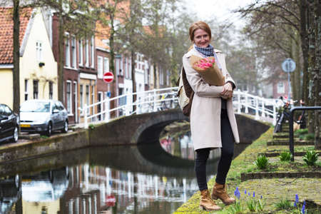 happy smiling girl holding a bouquet of tulips standing on a street of Amsterdamの写真素材