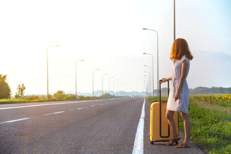 the girl and yellow suitcase at the  roadの写真素材