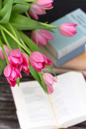 beautiful pink tulips in a vase and books against a brick wall backgroundの写真素材