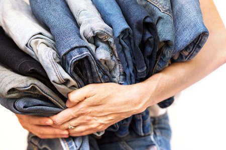 The girl holds a stack of jeans in her hands. cleaning in the closet.の写真素材