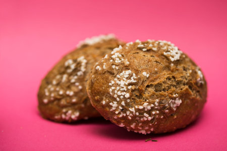 appetizing buns for sandwich with cumin and salt on a pink backgroundの写真素材
