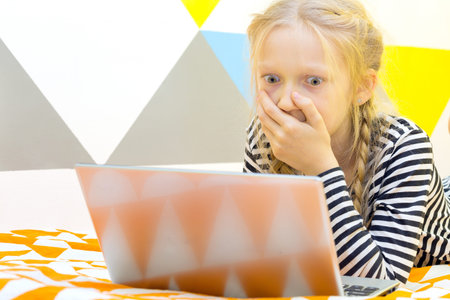 girl on the bed in the nursery play on a laptop