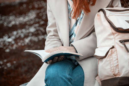 the girl is sitting on a park bench and reading a bookの写真素材